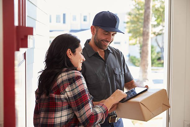 Woman Signing For Package From Courier At Home